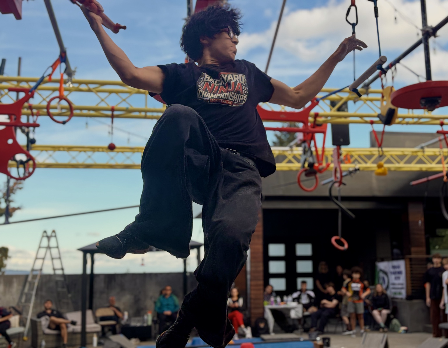 Bodhi Snow midair on an outdoor ninja obstacle course