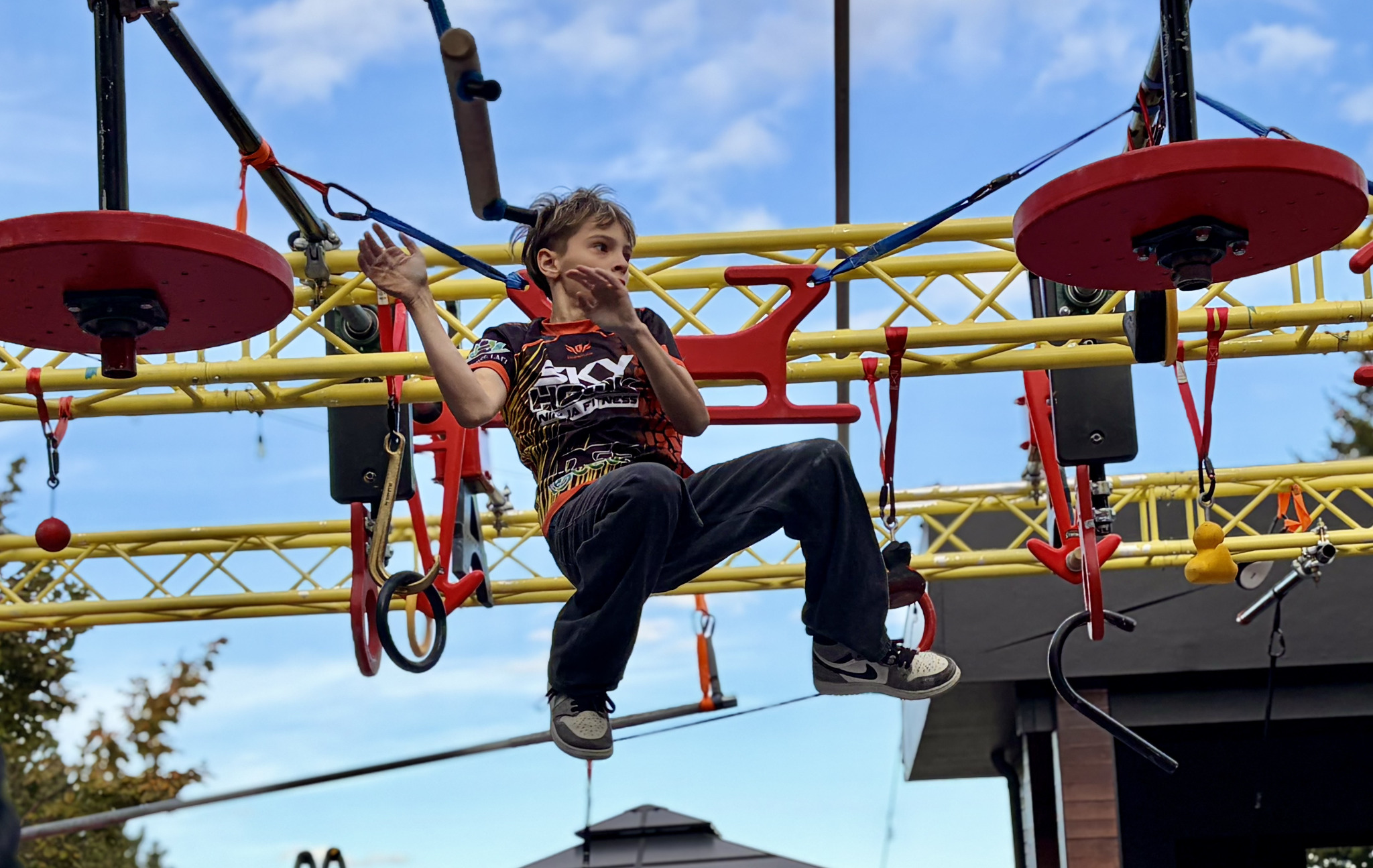 Brandon Steinfeld midair on an outdoor ninja obstacle course