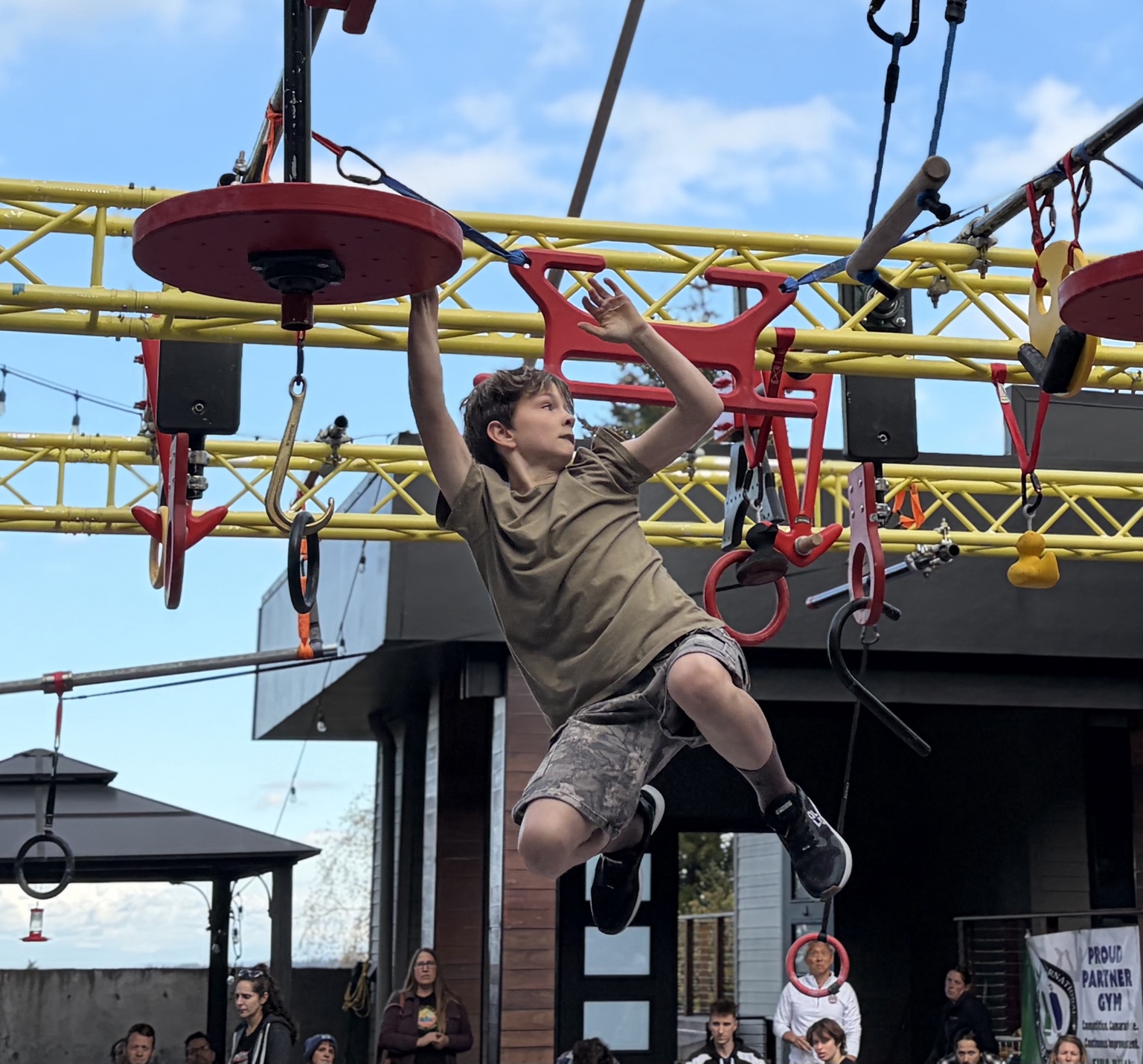 Harper Cleaver midair on an outdoor ninja obstacle course